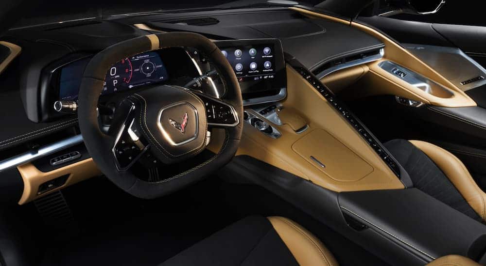 The front brown and black interior of a 2020 Chevy Corvette with an infotainment system is shown.