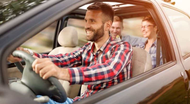 Friends are smiling while ride sharing in a used car.