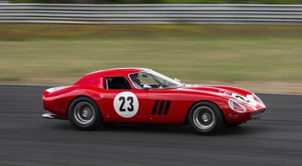 A red 1962 Ferrari 250 GTO, which is similar one of the most expensive used cars sold, is driving on a race track.