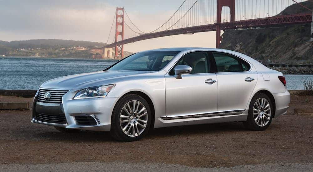 A silver 2016 Lexus LS 460 is parked in front of a bridge next to a lake.