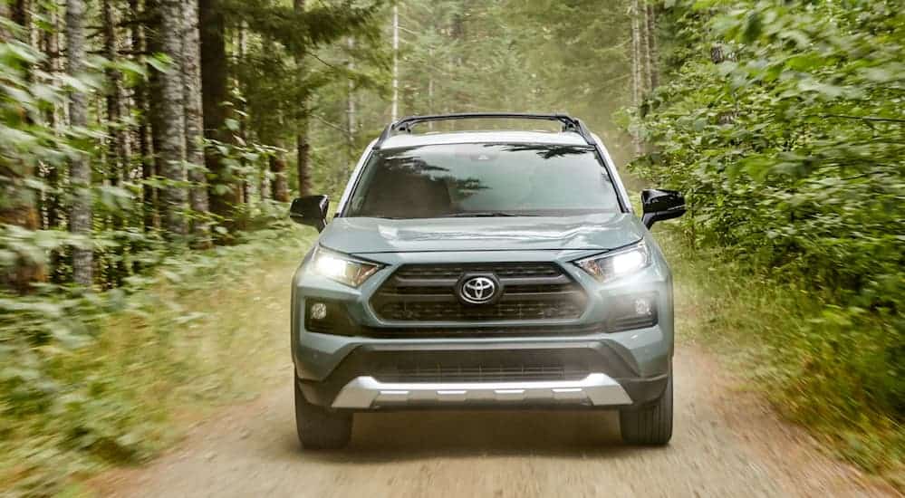 A 2019 Toyota RAV4 is driving on a dirt trail while facing forward. 