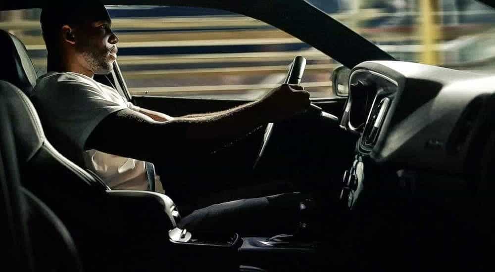 A man with his hands on the steering wheel is shown from the side in a 2020 Dodge Charger.