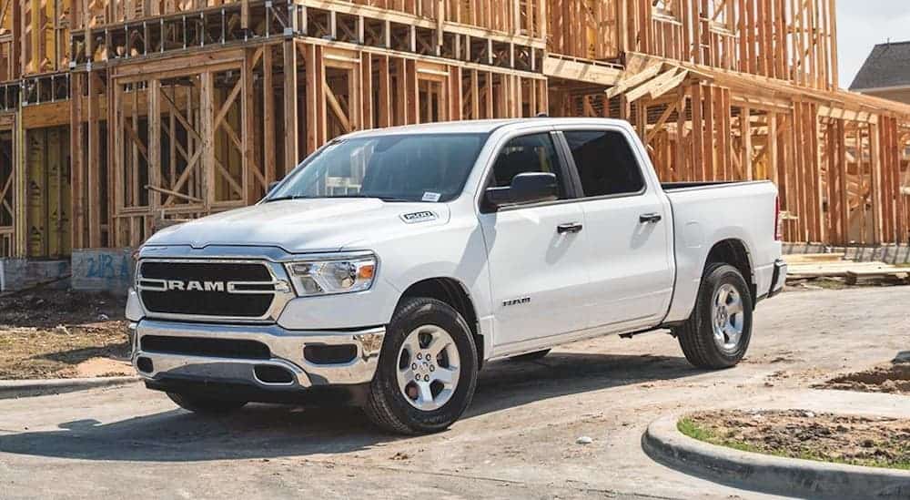 A white 2020 Ram 1500 is parked in front of a new home construction site.