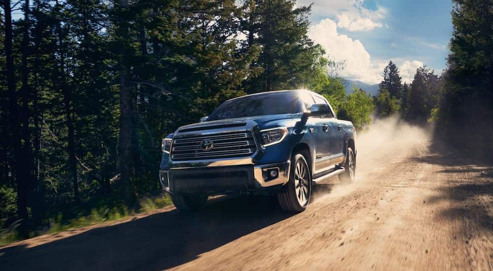 A dark blue 2020 Toyota Tundra is driving on a dirt road.
