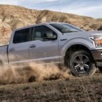 A silver 2020 Ford F-150, which wins when comparing the 2020 Ford F-150 vs 2020 Toyota Tundra, is off-roading with desert hills behind it.