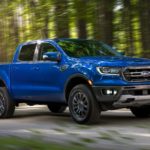 A blue 2020 Ford Ranger is driving on a road past blurred trees.