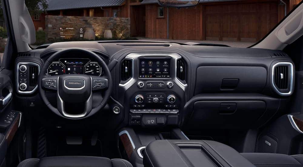 The front black leather interior of the 2020 GMC Sierra 1500 is shown with an infotainment system and a Head-Up display. 
