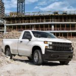 A white 2021 Chevy Silverado 1500 is parked between mounds of rubble at a construction site.