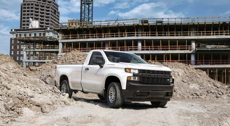 A white 2021 Chevy Silverado 1500 is parked between mounds of rubble at a construction site.