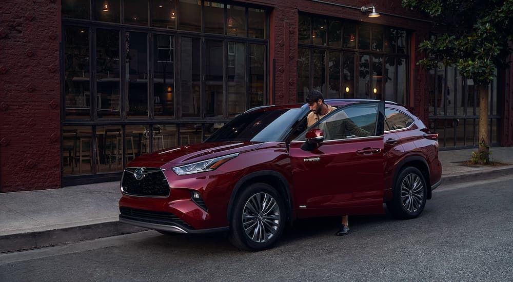 A dark red 2021 Toyota Highlander is shown from the side with a man getting in the vehicle.