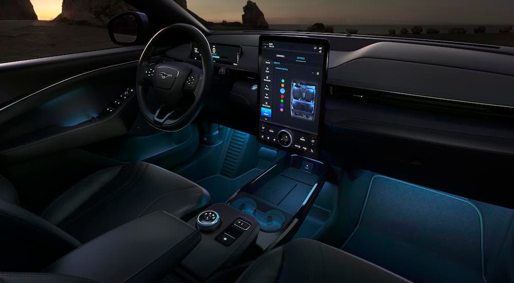The front black leather interior of the 2021 Ford Mustang Mach-E is shown with blue accent lights. 