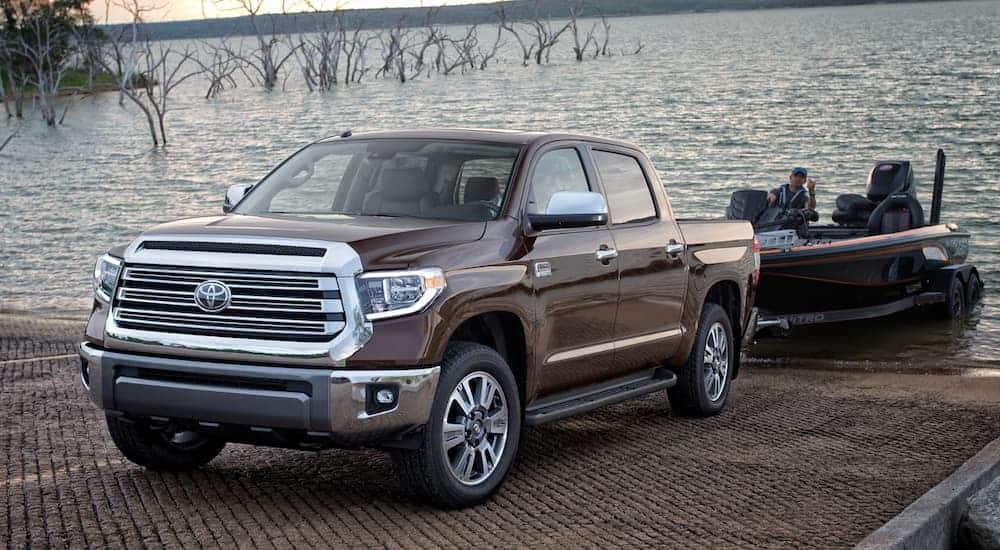 A brown 2020 Toyota Tundra, which is a popular truck among the Toyota models, is backing up a boat into a lake. 