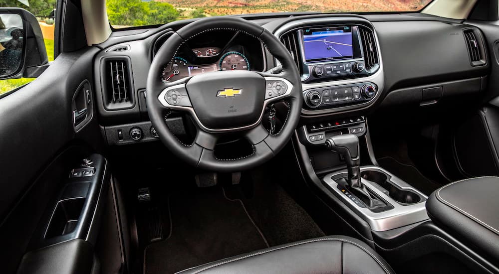 The front black leather interior of a 2020 Chevy Colorado is shown with an infotainment system. 