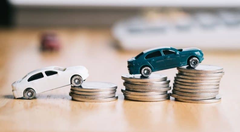 Two toy cars are driving on to stacks of coins.
