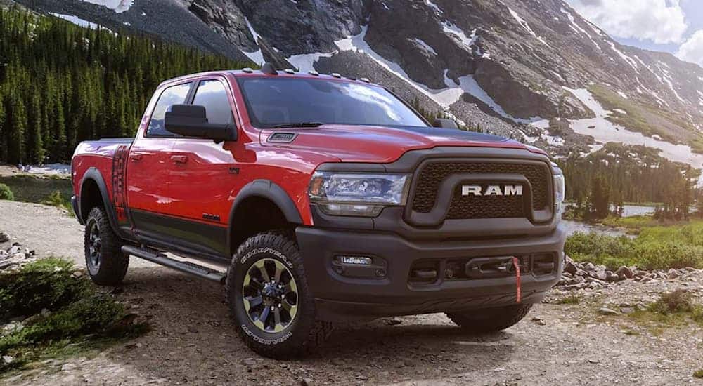 A red 2019 Ram 2500 Power Wagon, which is a popular option among used trucks for sale, is parked on a dirt trail with snow covered mountains in the distance. 