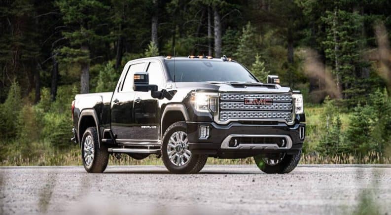 A black 2020 GMC Sierra 2500HD is parked on a gravel patch that's surrounded by trees.