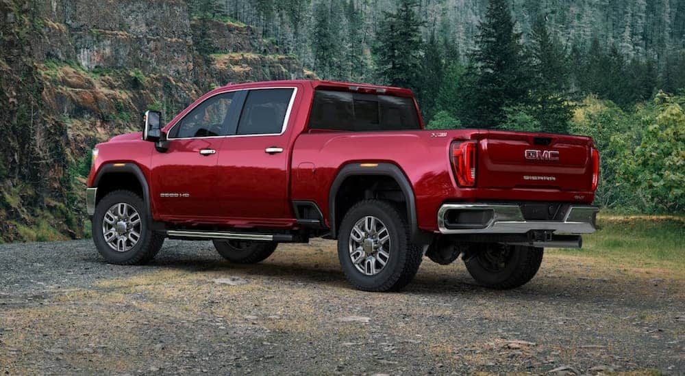 A red 2020 GMC Sierra 2500HD crew cab is parked next to a rock wall that's covered in moss.