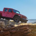 A red 2020 Jeep Gladiator is on a rocky ledge that's overlooking a valley.