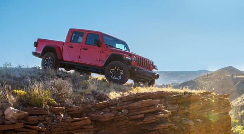 A red 2020 Jeep Gladiator is on a rocky ledge that's overlooking a valley.