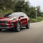A red Sportage drives off on a rural road with a victory in 2020 Kia Sportage vs 2020 Jeep Cherokee.