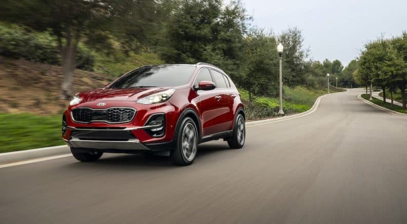 A red Sportage drives off on a rural road with a victory in 2020 Kia Sportage vs 2020 Jeep Cherokee.