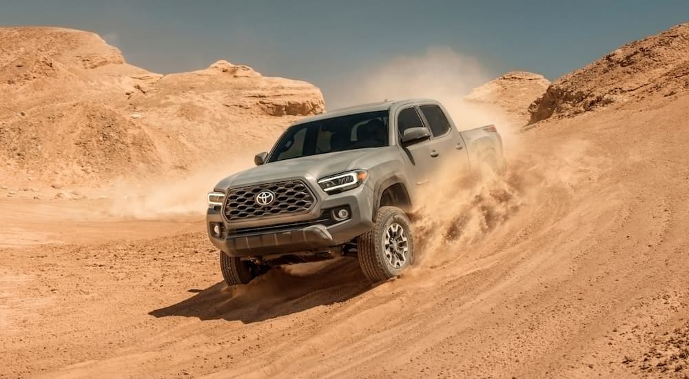 A tan 2020 Toyota Tacoma TRD Off-Road edition is driving through the desert sand.