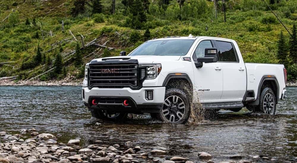 A white 2020 GMC Sierra HD AT4 is crossing a river.