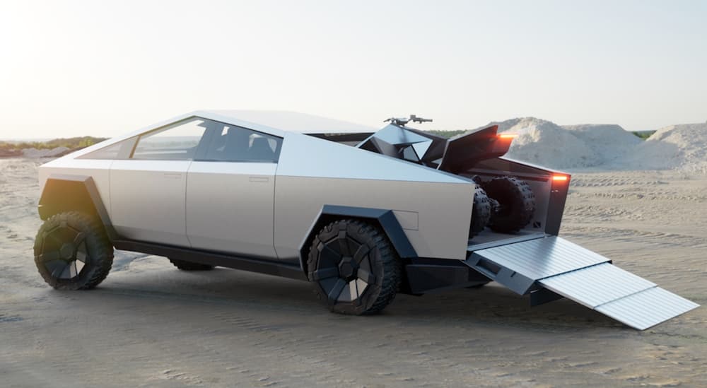 An ATV is in the bed of a Tesla Cybertruck that's parked in the desert.