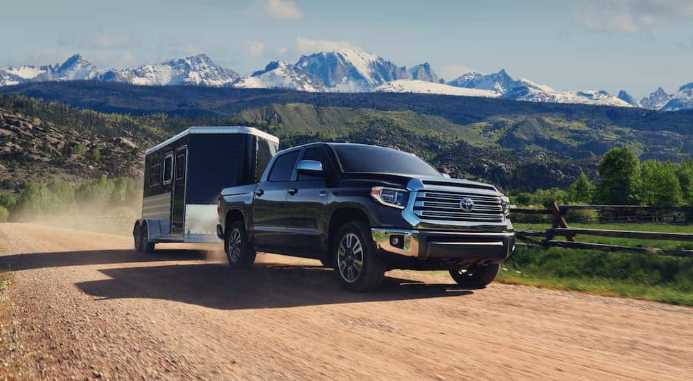 A black 2020 Toyota Tundra is towing a black enclosed trailer on a dirt road.