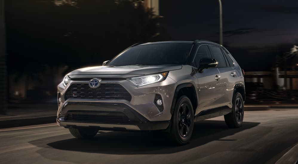 A silver 2020 RAV4 is driving through a city at night.