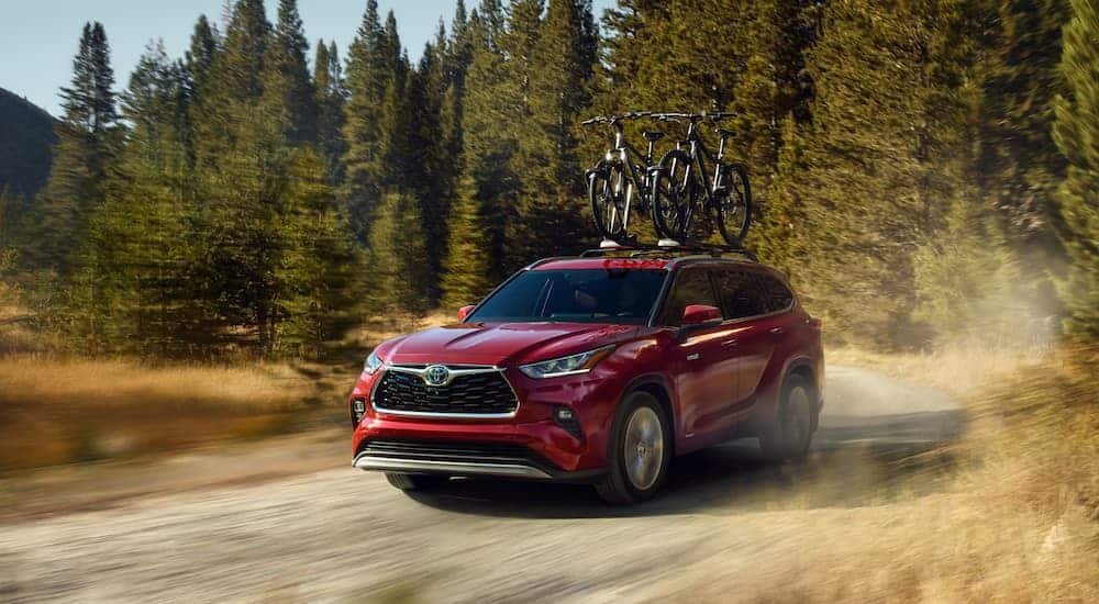 A red 2020 Toyota Highlander is driving on a dirt road.