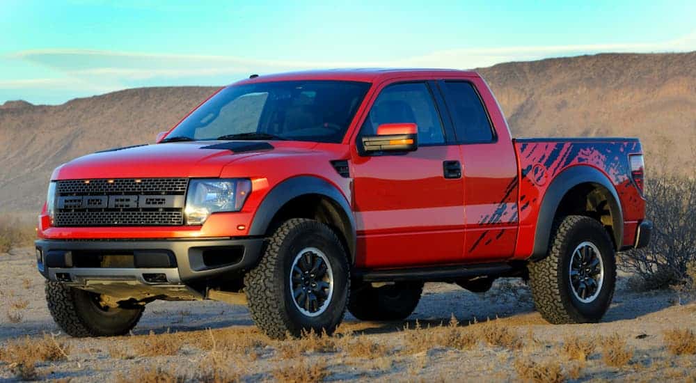 A red 2010 Ford Raptor is parked in a desert.