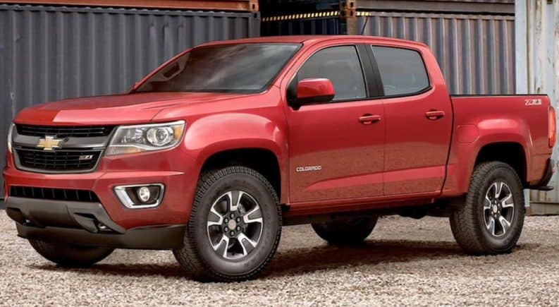 A red 2020 Chevy Colorado is parked next to metal shipping containers.