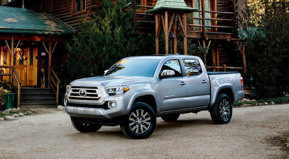 A silver 2020 Toyota Tacoma is parked in front of a log cabin. 