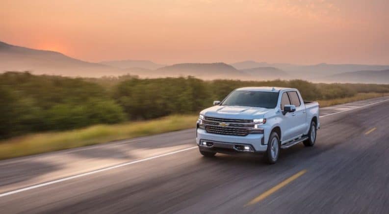 A white 2020 Chevy Silverado 1500 is driving at sunset after winning the 2020 Chevy Silverado vs 2020 Nissan Titan comparison.