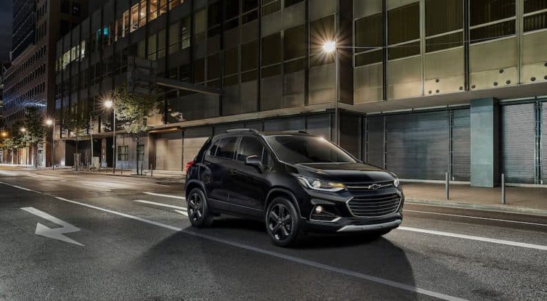 A black 2020 Chevy Trax, which wins when comparing the 2020 Chevy Trax vs 2020 Buick Encore, is driving on a dark lit road at night.