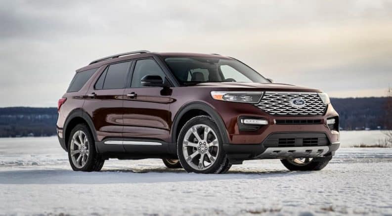 A burgundy 2020 Ford Explorer, which wins when comparing the 2020 Ford Explorer vs 2020 Chevy Traverse, is parked on a snow covered parking lot.