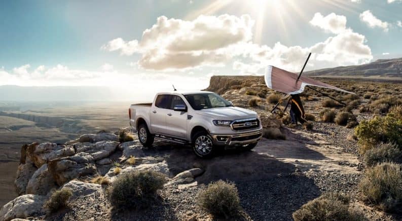 A silver 2020 Ford Ranger is parked on a cliff with a hang glider.