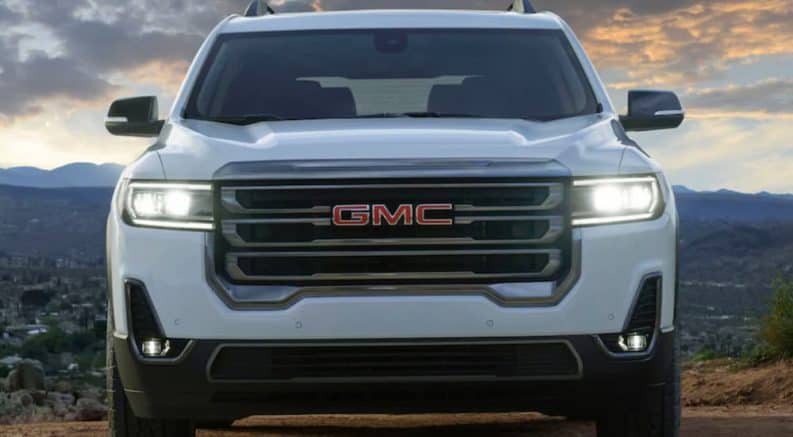 A white 2020 GMC Acadia is facing forward while parked on a hill.