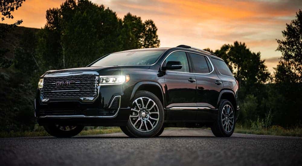 A black 2020 GMC Acadia Denali is parked in front of a vibrant sunset.