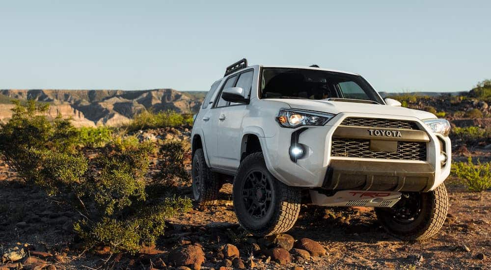 A white 2020 Toyota 4Runner climbing over rocks, but it couldn't win the competition of 2020 GMC Acadia vs 2020 Toyota 4Runner.