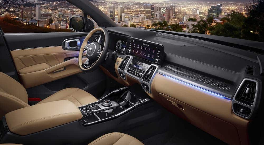 The two-tone beige and black interior of a 2021 Kia Sorento that is overlooking a city at night.