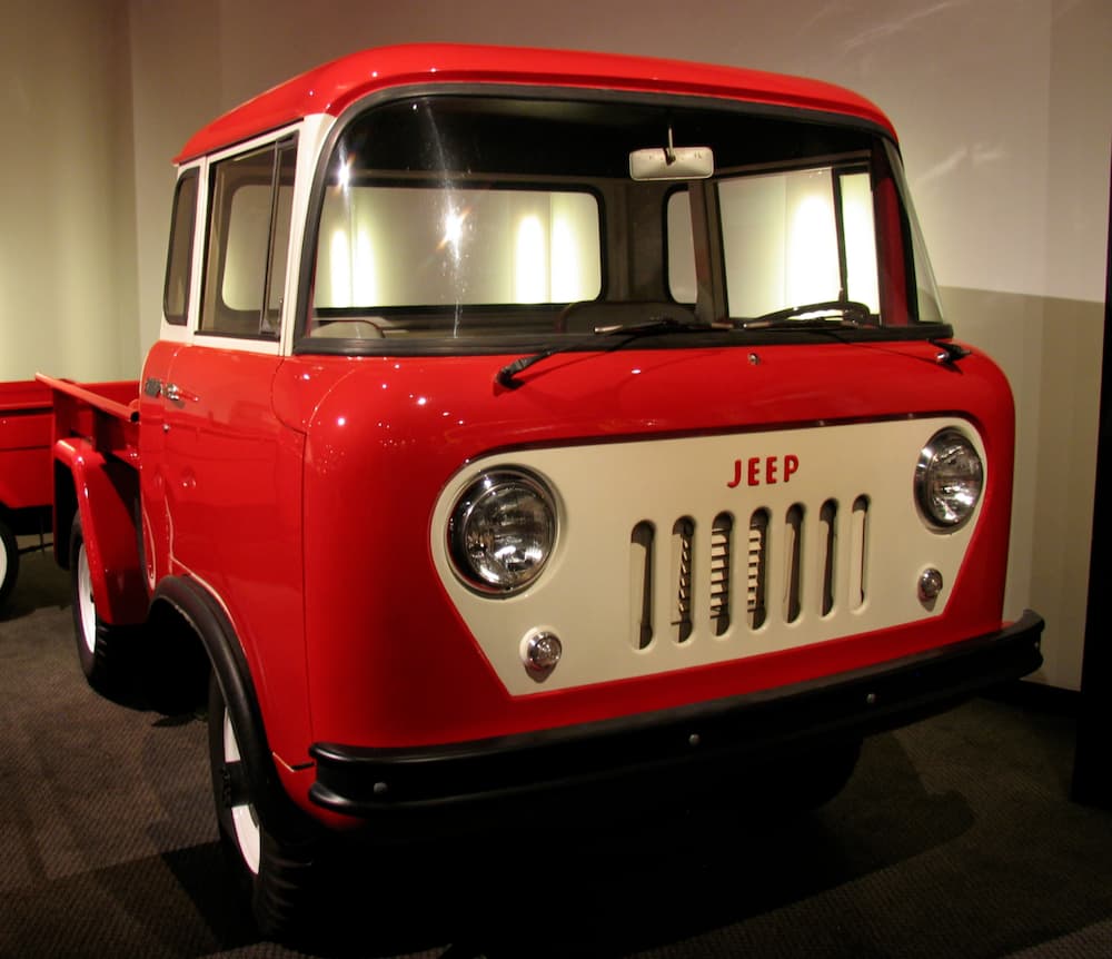A red Jeep Forward Control is in a showroom display.