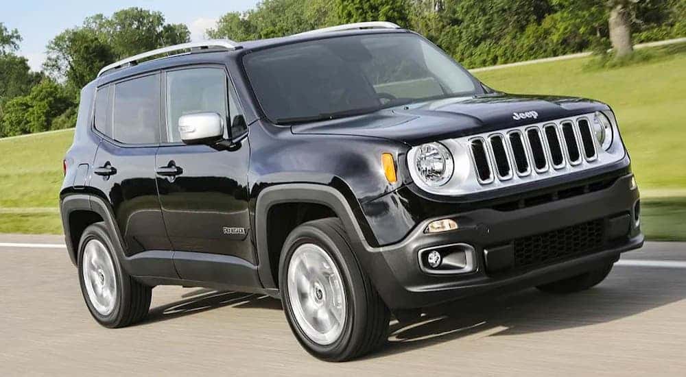 A black 2017 Jeep Renegade is driving on a rural road.