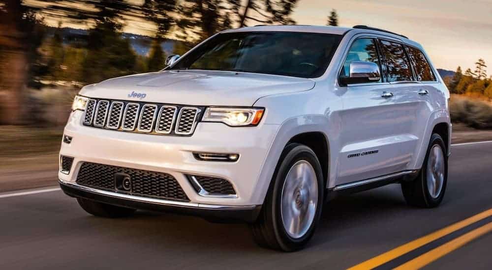 A white 2018 Jeep Grand Cherokee is driving at sunset.