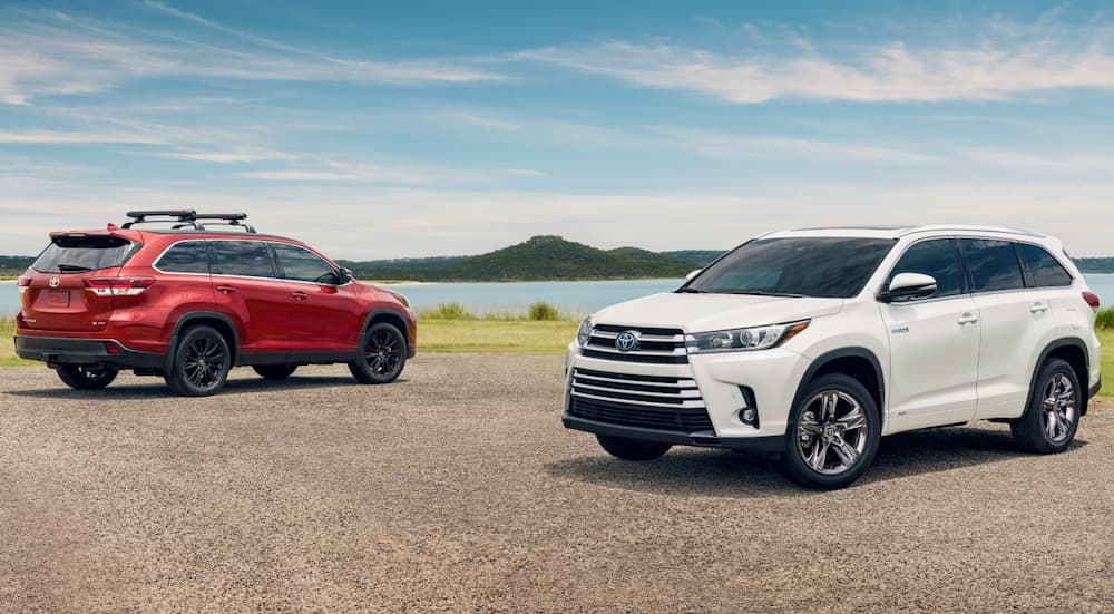 A red 2019 Toyota Highlander is parked behind a white one at the beach.