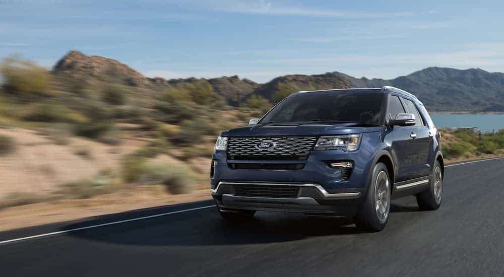 A blue 2017 Ford Explorer is driving away from mountains.