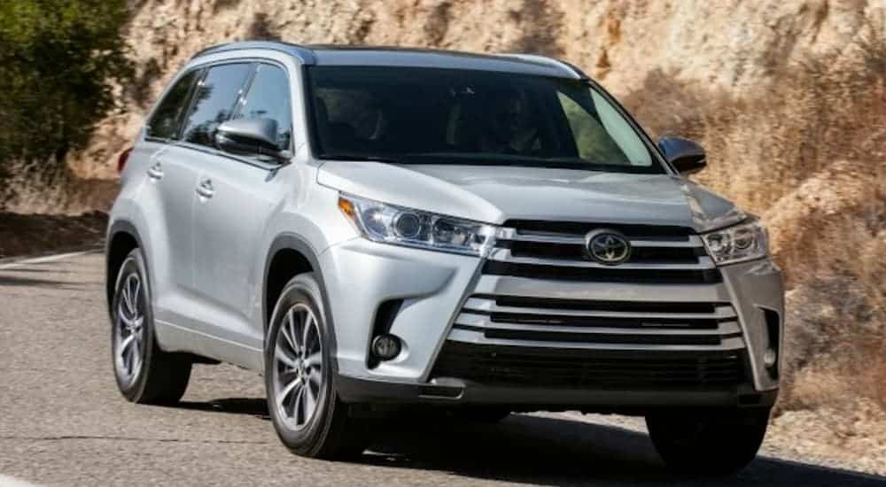 A silver 2017 Toyota Highlander is driving past rock walls.