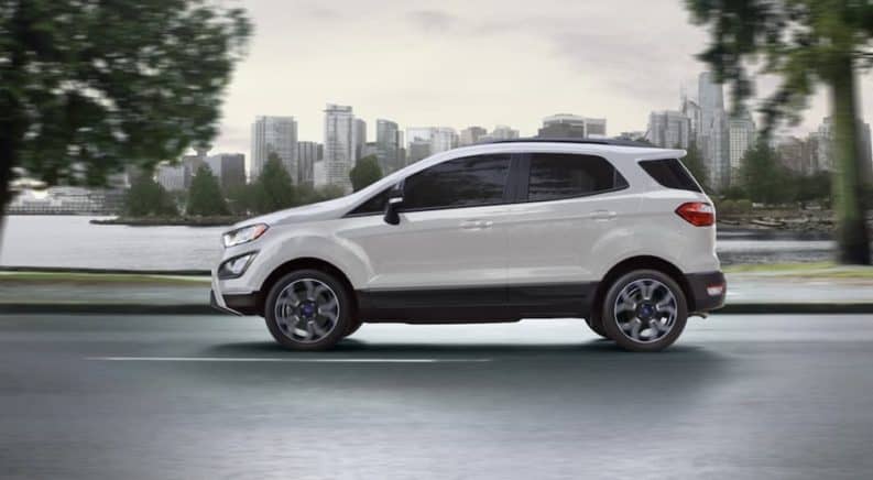 A white 2020 Ecosport is shown from the side driving past a city skyline.