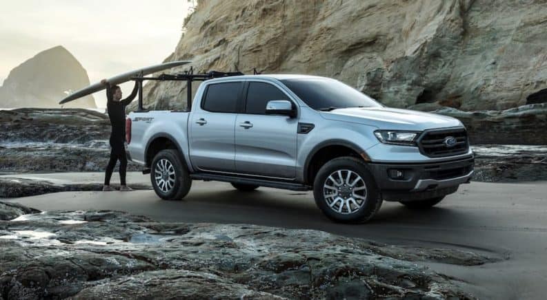 A surfer is loading up his silver 2020 Ford Ranger on the beach.